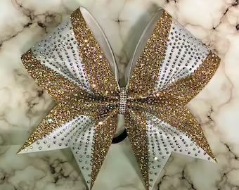 a white and gold bow on top of a marble counter with lots of sparkles