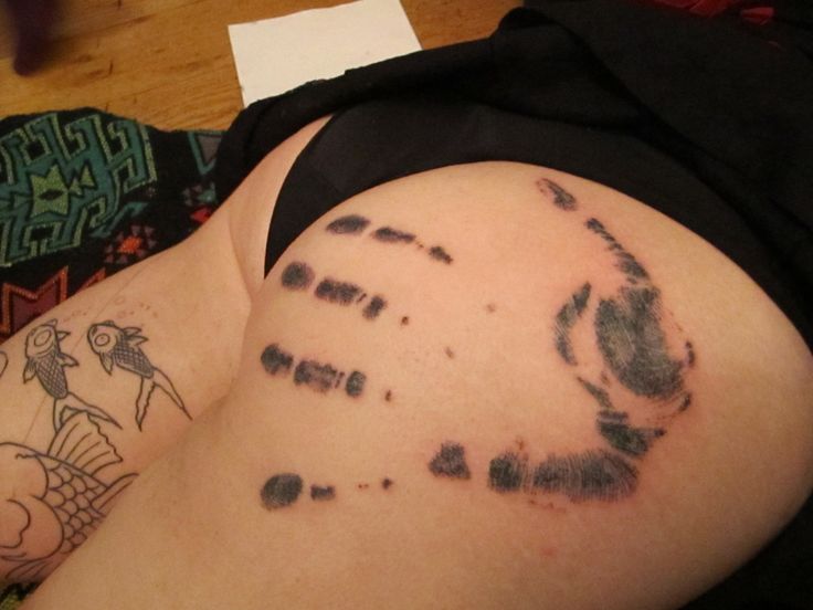 a person laying on the floor with tattoos on their stomach