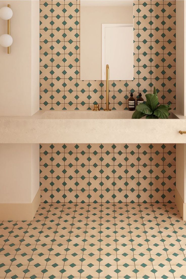 the bathroom is decorated with green and white geometric tiles, along with a gold faucet