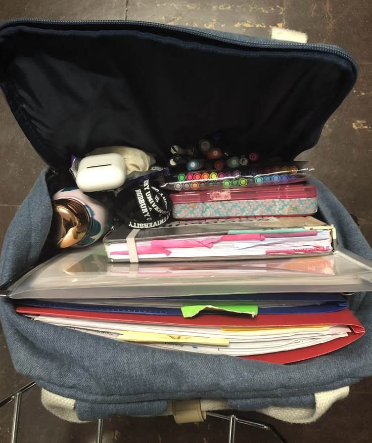 an open suitcase filled with lots of papers and other items sitting on top of a chair