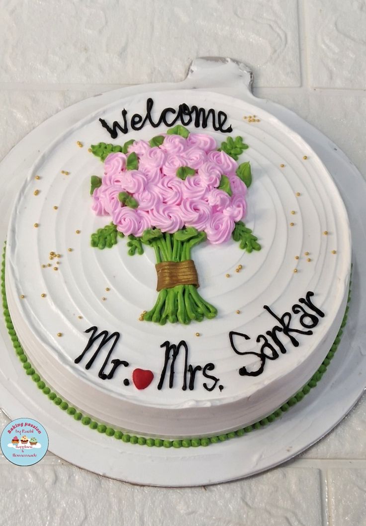 a white cake with pink roses on it and the words welcome mr mrs sarga written in black