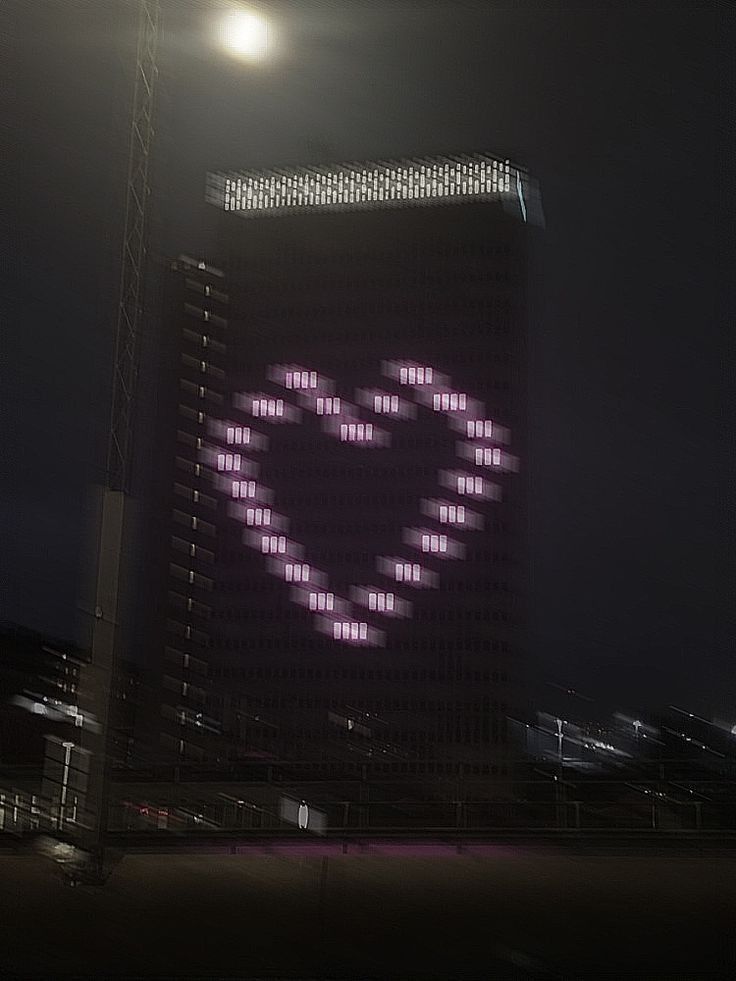 a large building with a heart on it's side in the dark night time