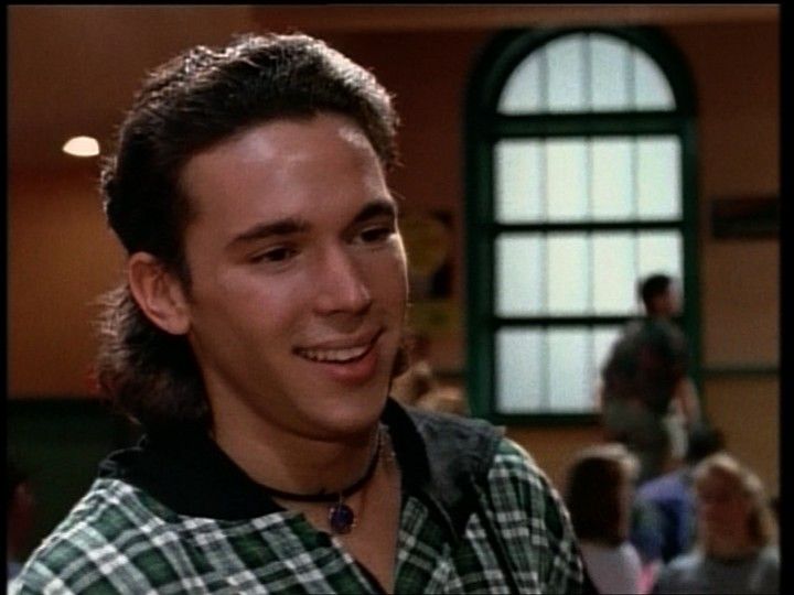 the young man is smiling for the camera in front of an audience, wearing a green and white checkered shirt