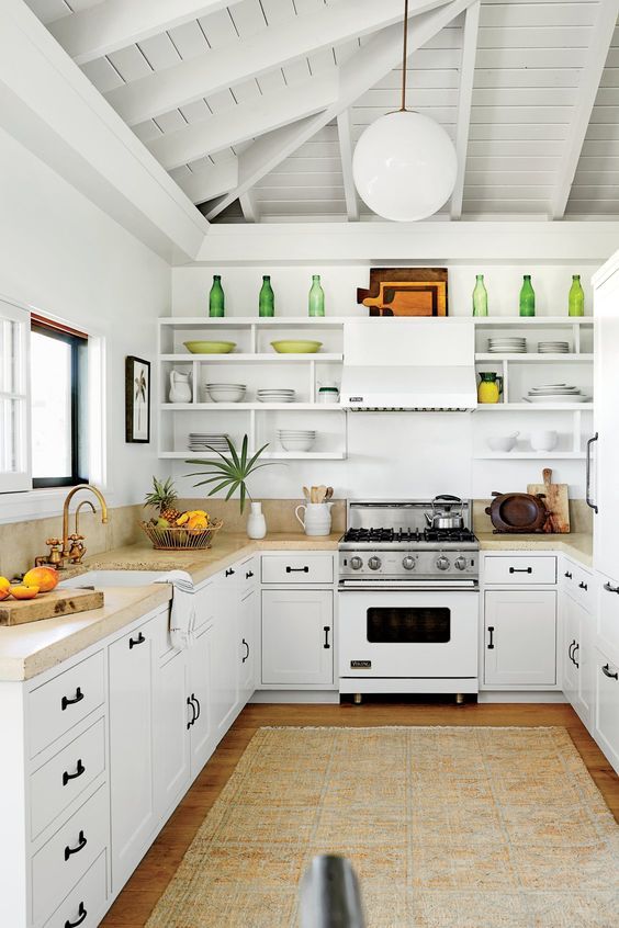 a kitchen with white cabinets and open shelves on the wall, along with an area rug