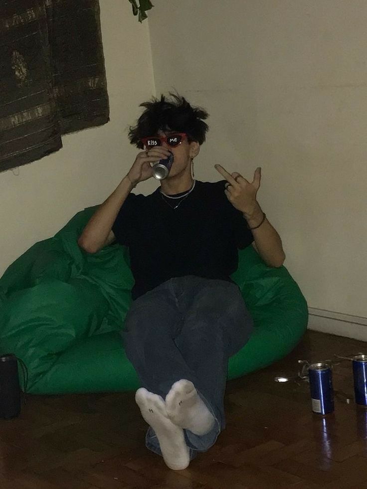 a man sitting on a bean bag chair drinking from a bottle