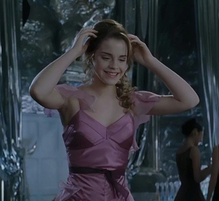 a woman in a pink dress is smiling