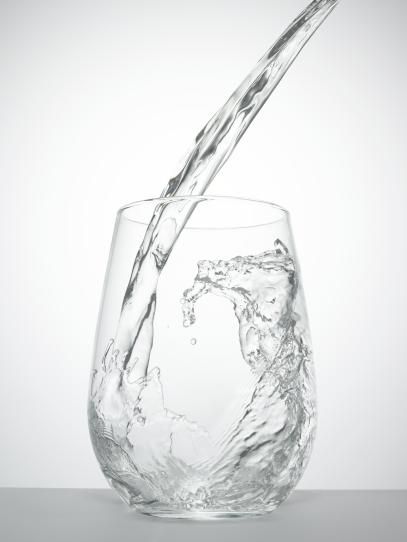 a glass filled with water being poured into it