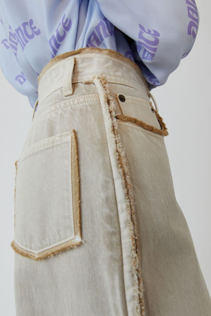 the back of a woman's pants with buttons and fraying on it, in front of a white background