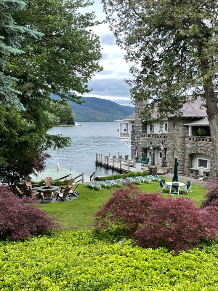 the lawn is full of chairs and tables by the water