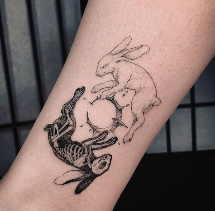 a tattoo on the leg of a person with two rabbits