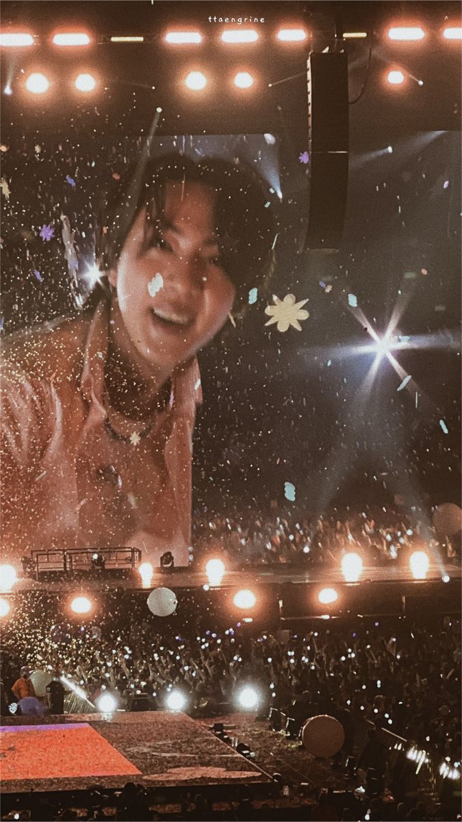 a man standing on top of a stage in front of a large screen with lights