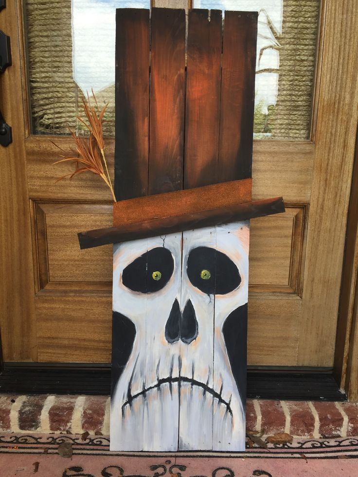 a painted skull wearing a hat on the front door porch with an open wooden door