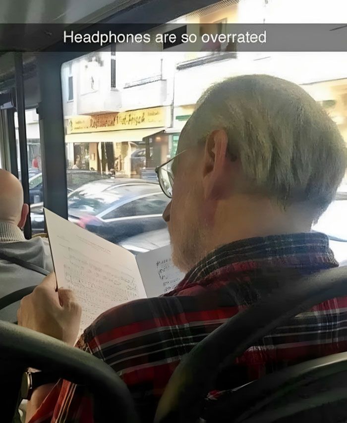 a man sitting on a bus holding a paper in his hand and looking out the window