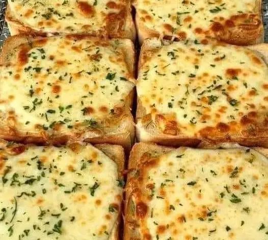 several square pizzas with cheese and herbs on them