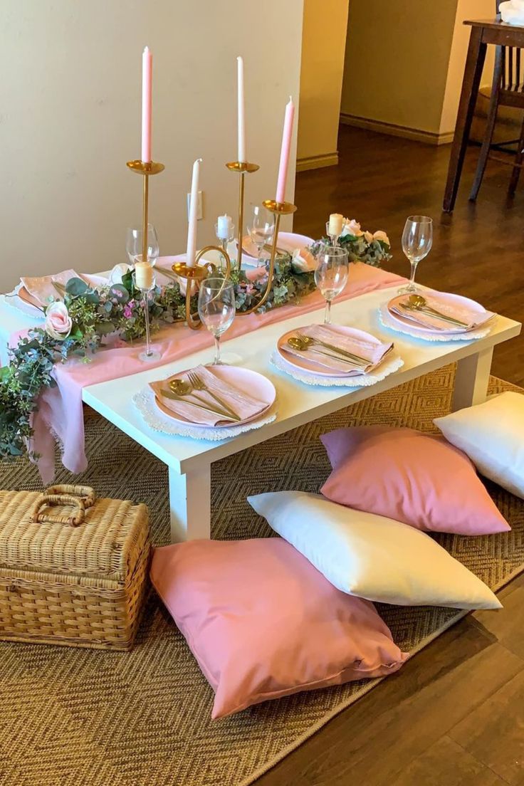 the table is set with pink and white pillows