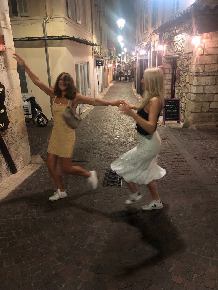 two women dancing in the street at night