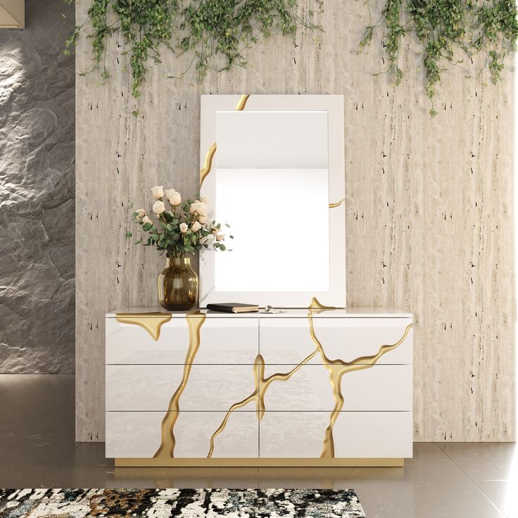 a white and gold dresser sitting next to a mirror