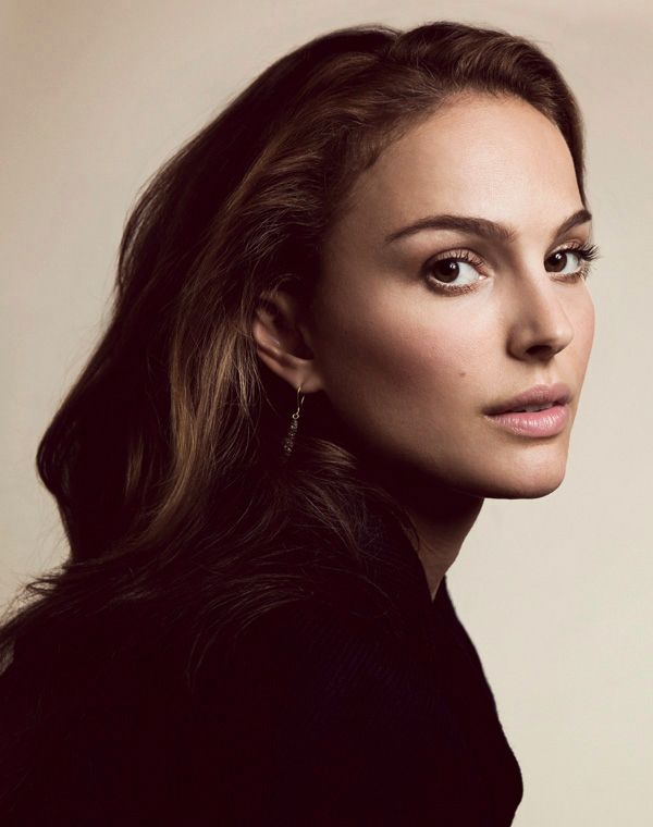 a woman with long hair is posing for the camera and looking at the camera while wearing earrings