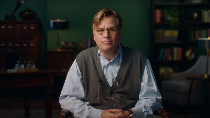 a man sitting at a table in front of a book shelf