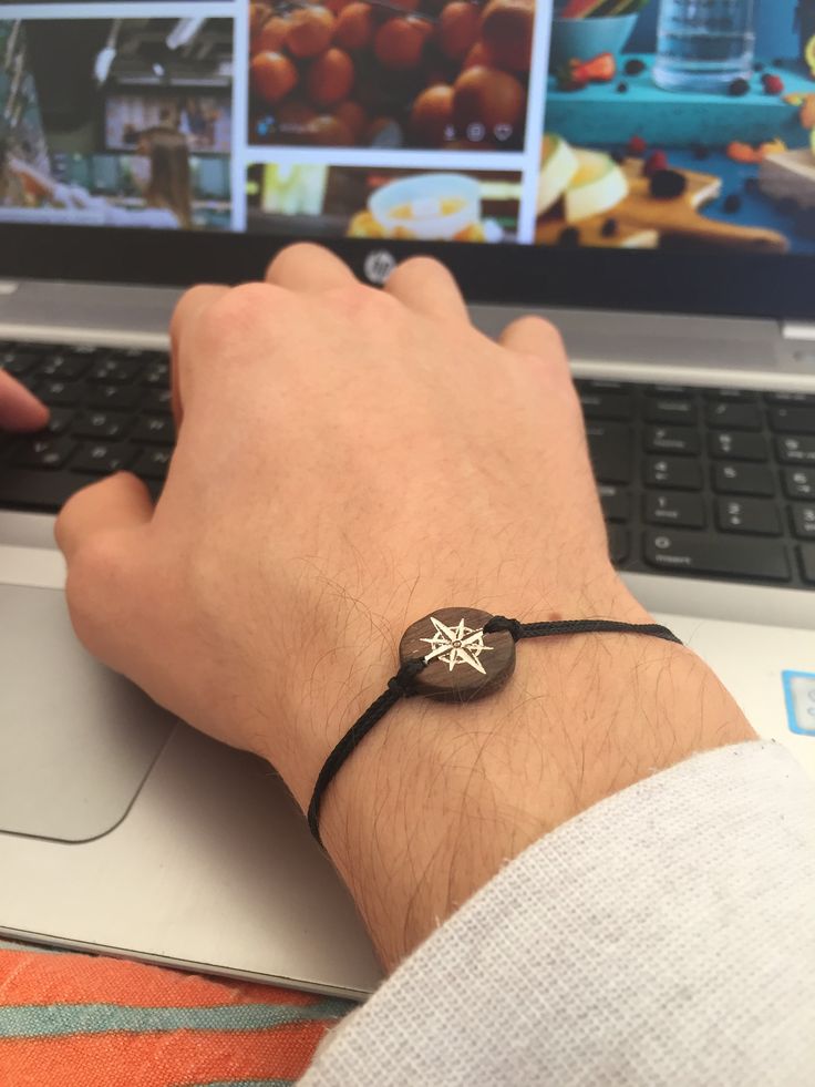 a person wearing a black bracelet on their wrist using a laptop