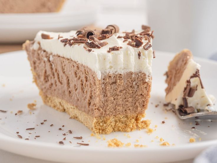 a piece of cake on a white plate with a fork next to it and another slice in the background