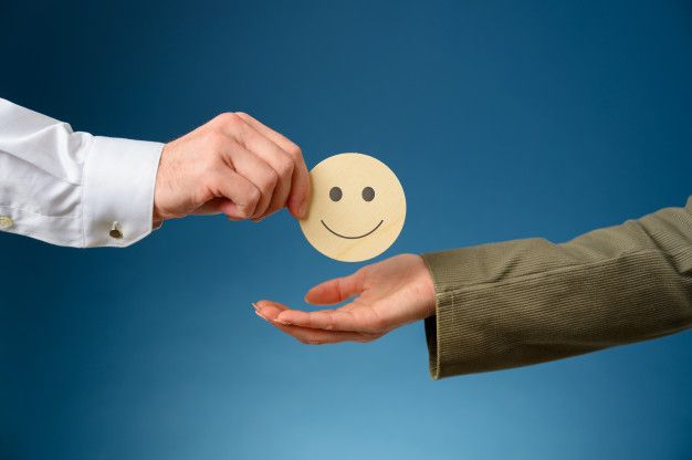 two people are handing each other a smiley face