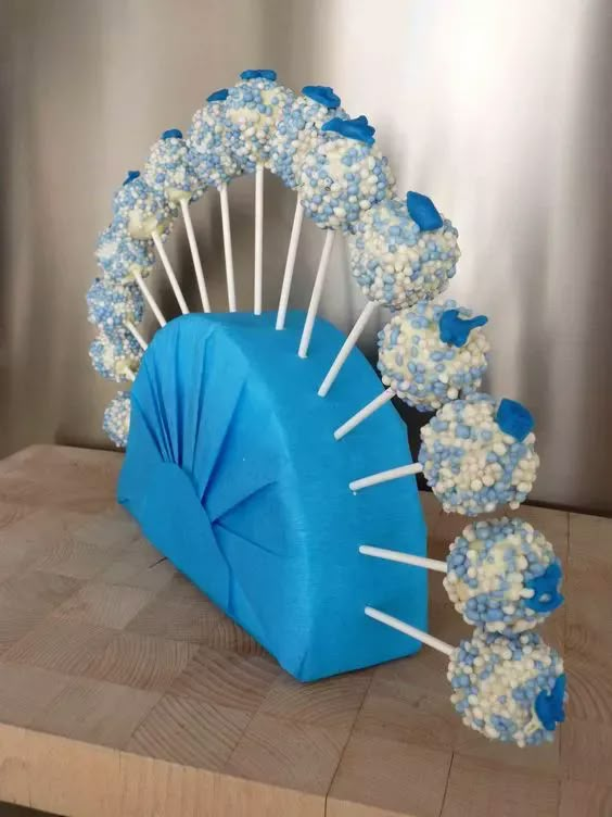 blue and white cake pops arranged on a wooden table with an umbrella made out of them