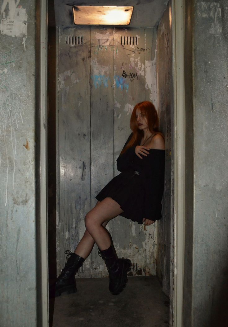 a woman is sitting in an elevator with her legs up on the wall and looking at the camera