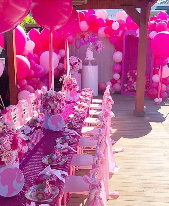 a table set up with pink and white balloons