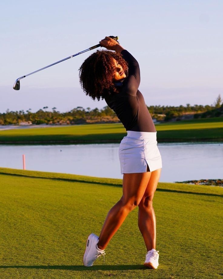 a woman is swinging her golf club on the course