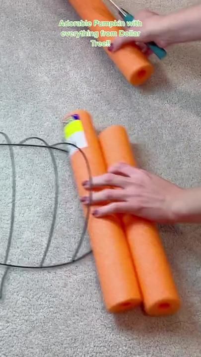 two hands are holding some carrots on the floor with wires attached to them and one hand is using scissors