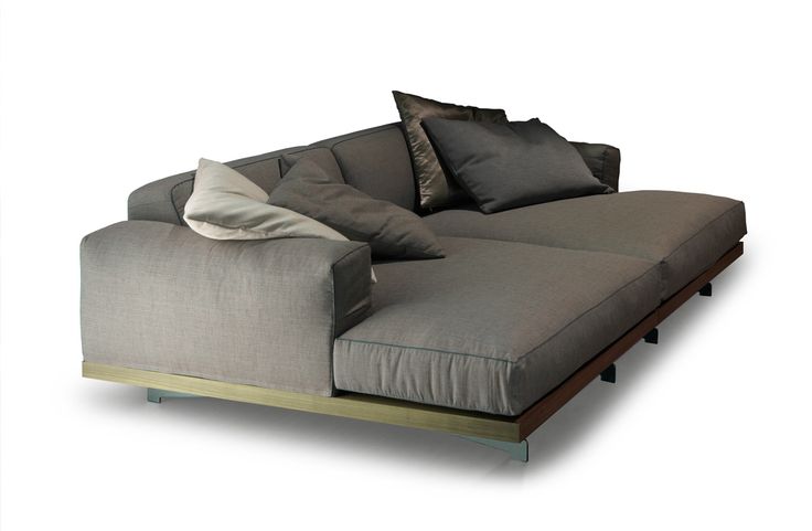 a large gray couch with pillows on it's back and side rests against a white background