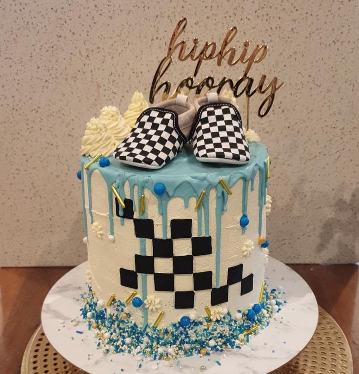 a birthday cake with blue icing and black and white checkered shoes on top