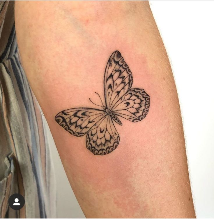 a black and white butterfly tattoo on the arm