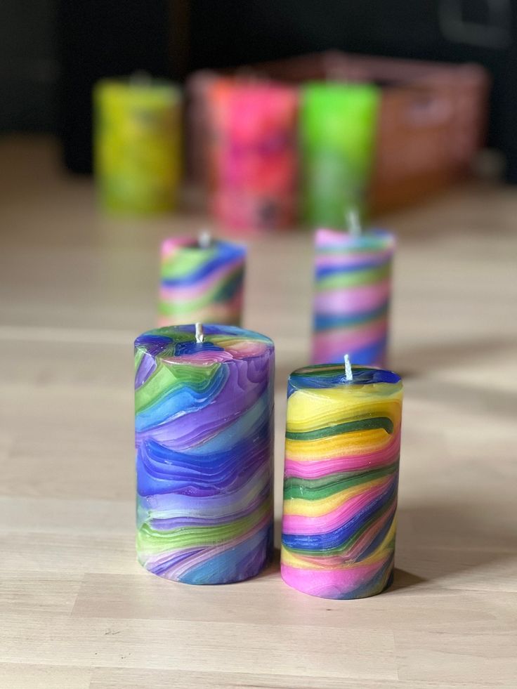 three colorful candles sitting on top of a wooden table