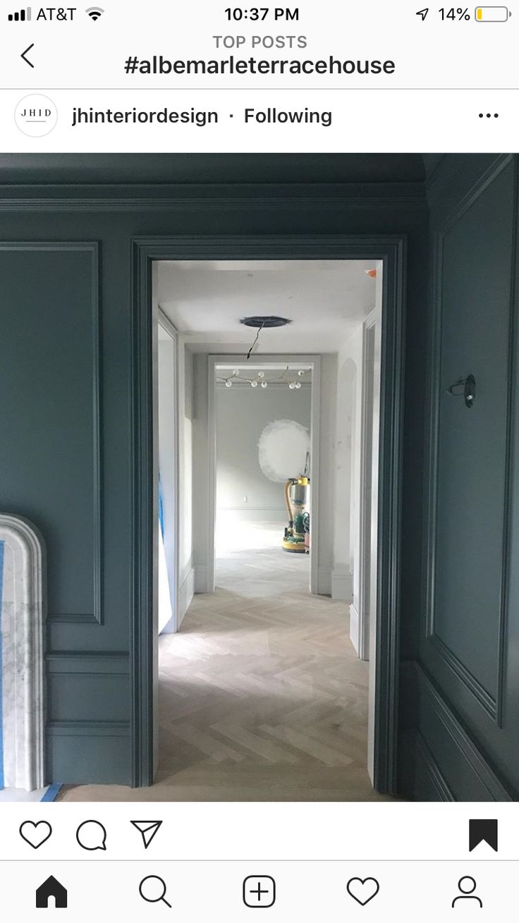 an instagram photo of a hallway with dark green walls and white trim on the walls