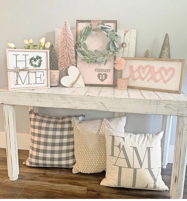 a white table topped with lots of pillows and other decorating items on top of it