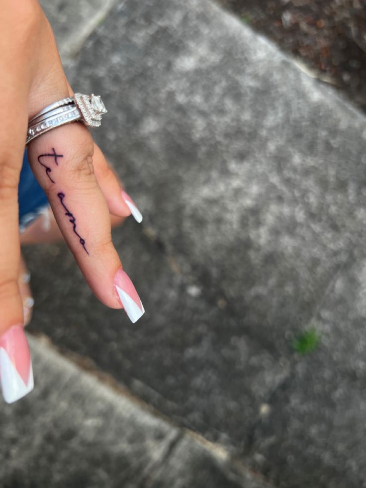 a woman's hand with a cross tattoo on it