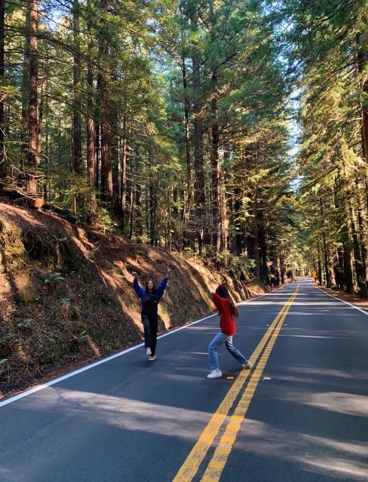 two people are running down the road in the woods