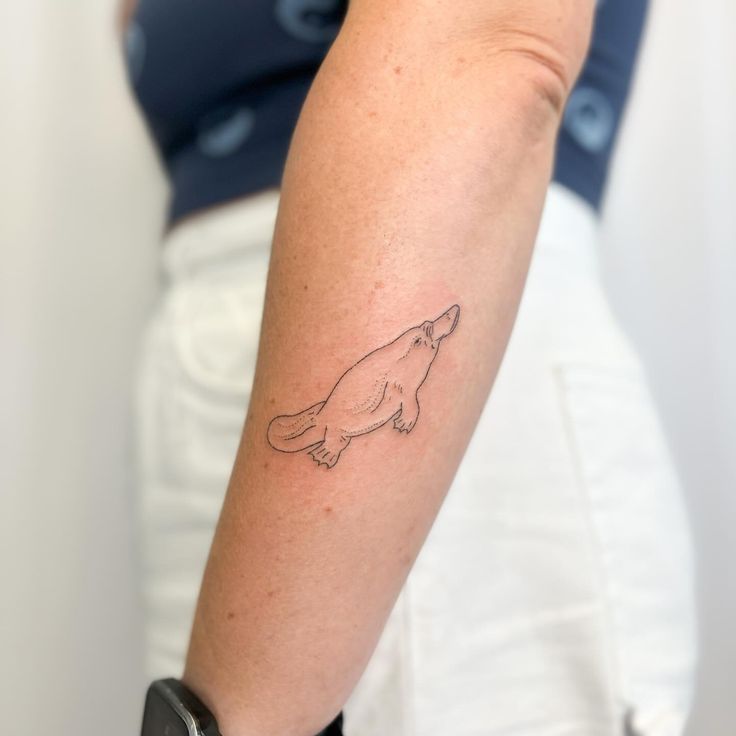 a woman's arm with a small bird tattoo on the left side of her arm