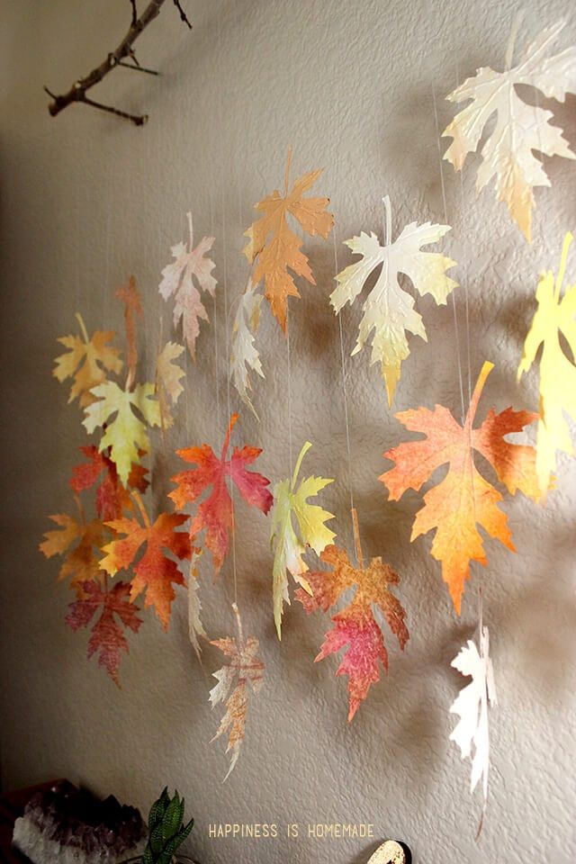 an image of autumn leaves hanging on the wall in front of a clock and tree branch