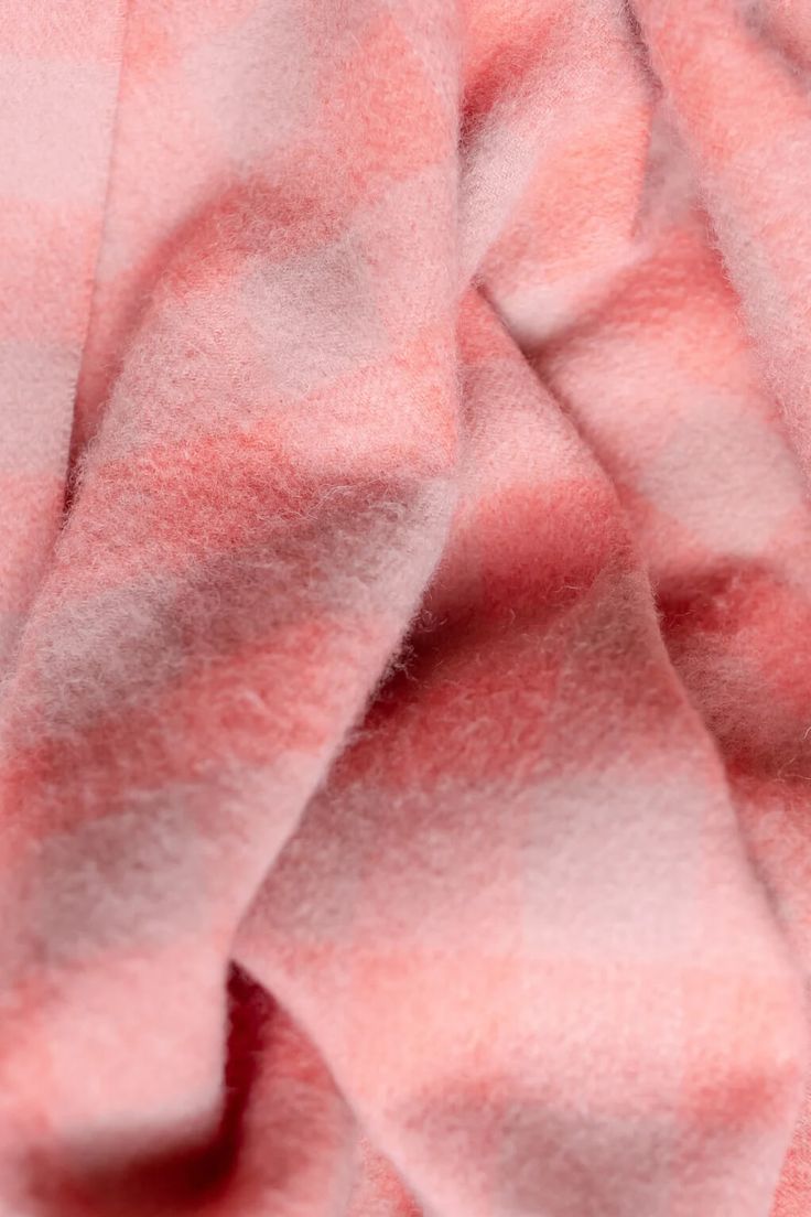 a pink and white checkered blanket laying on top of a bed sheet with no sheets