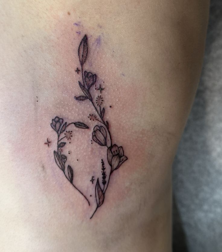 a small tattoo on the side of a woman's stomach with flowers growing out of it