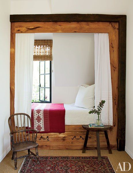 a bed sitting under a window next to a wooden frame