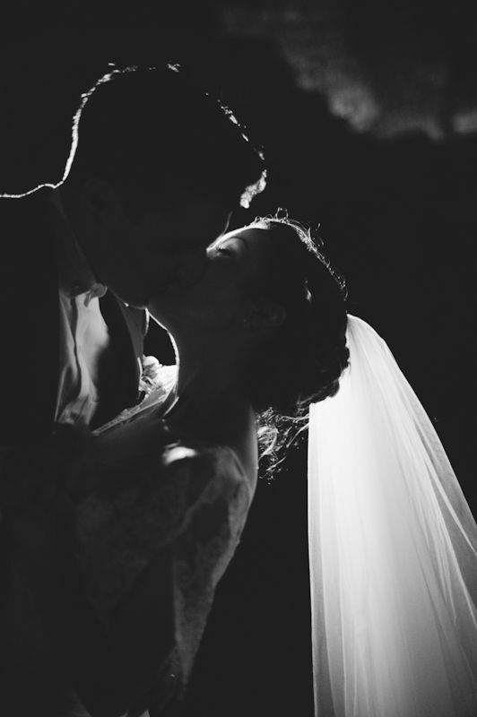 a bride and groom kissing in the dark