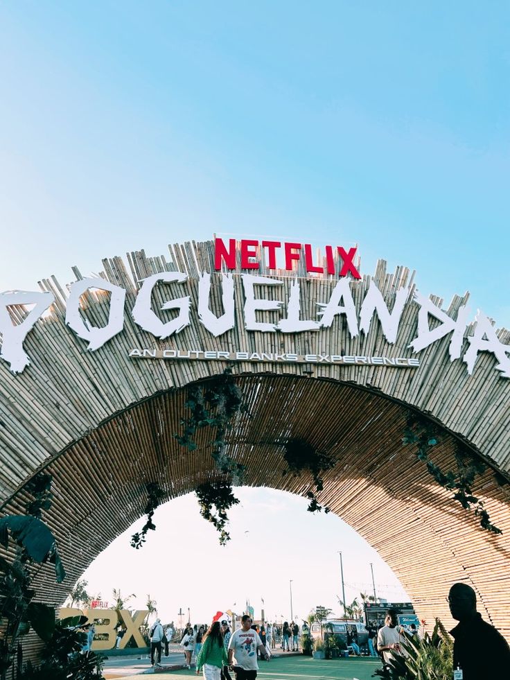 people walking under a wooden structure with the words netflix written on it