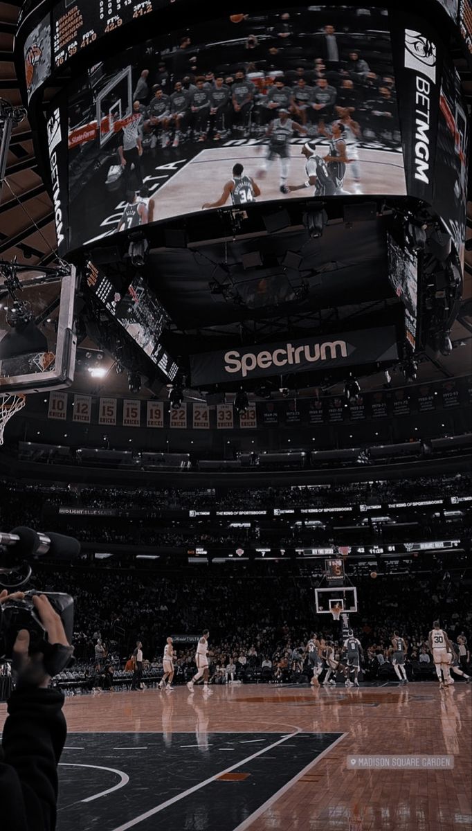 the inside of a basketball arena with people watching and taking pictures on their cell phones