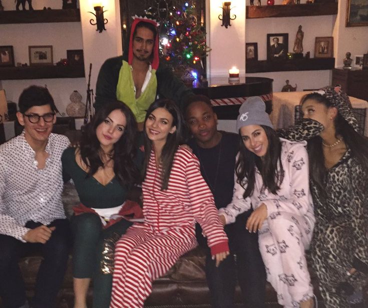 a group of people sitting next to each other in front of a christmas tree