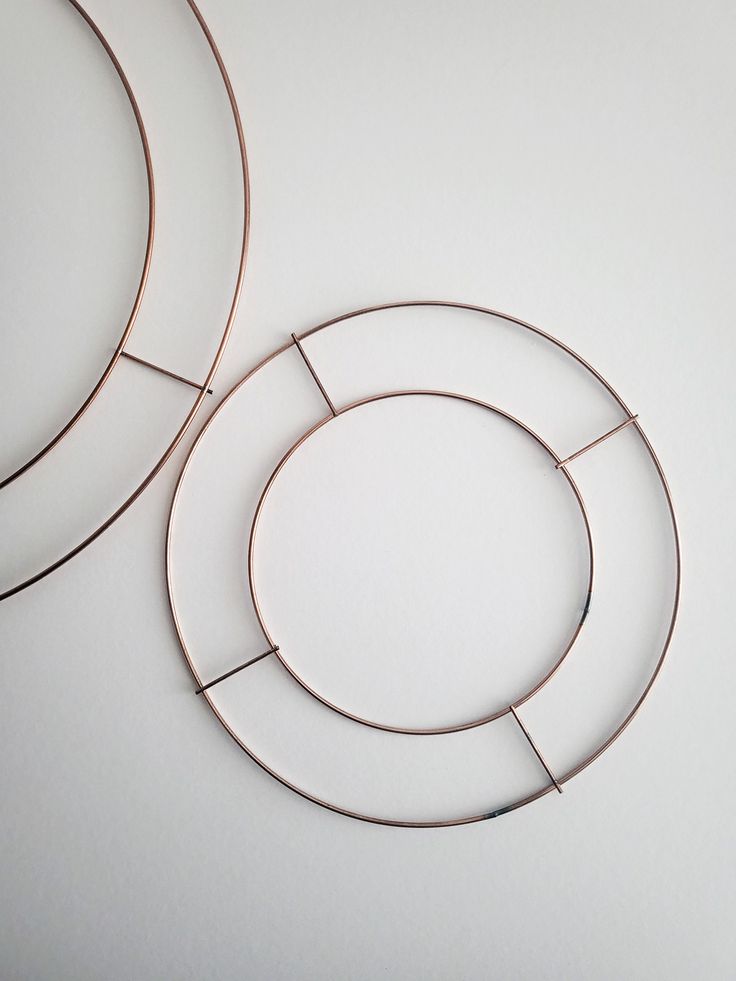 two metal hoops sitting next to each other on a white surface with one circle in the middle