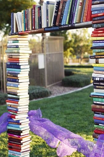 a tall stack of books sitting on top of a lush green field